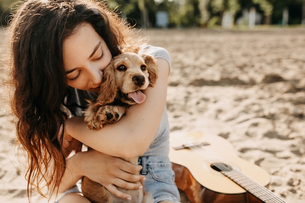 Mulher jovem na praia, abraçando o cachorro