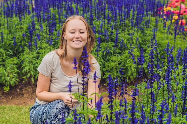 Mulher jovem na superfície de flores azul salvia farinacea florescendo no jardim