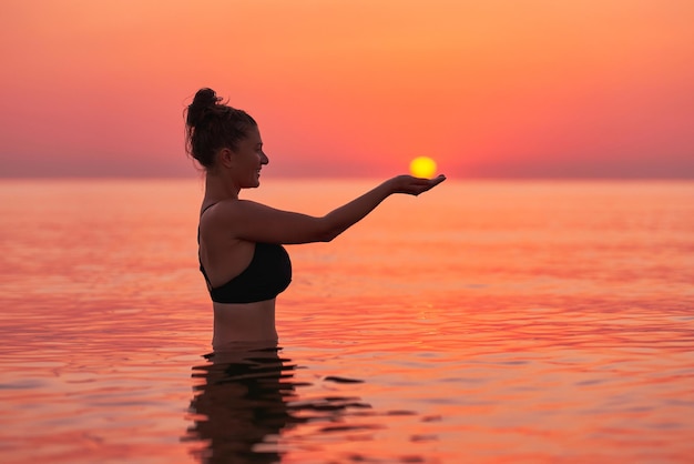 Mulher jovem nadando no mar ao nascer do sol