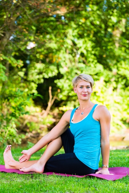 Mulher jovem no parque da cidade fazendo ioga ou se aquecendo para se exercitar