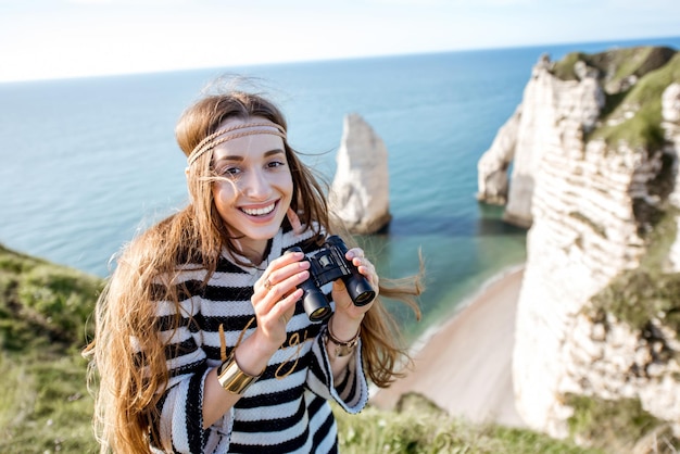 Mulher jovem olhando com binóculos na famosa costa rochosa perto da cidade de Etretat, na França