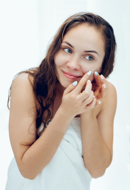 Mulher jovem olhando e espremer acne em um rosto na frente do espelho. Garota feia com problemas de pele, adolescente com espinhas. Cuidados com a pele. Beleza