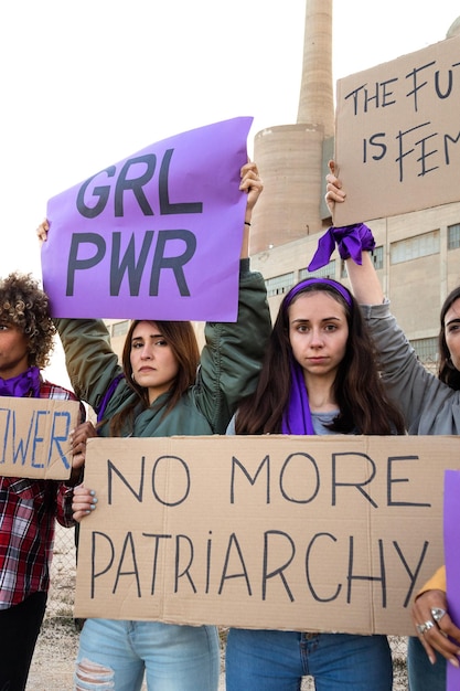 Mulher jovem olhando para a câmera segurando bandeira do patriarcado em demonstração feminista vertical