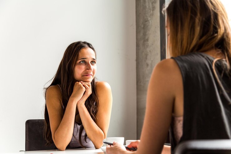 Foto mulher jovem olhando para baixo enquanto está sentada na mesa