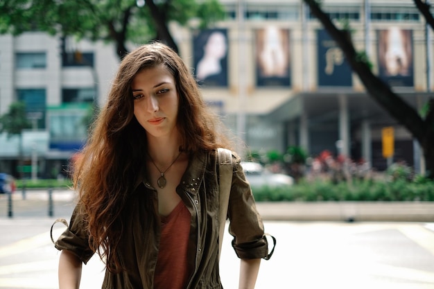 Mulher jovem olhando para longe enquanto está de pé na rua