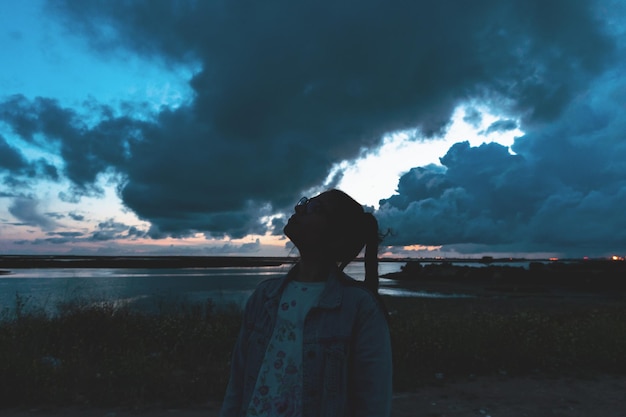 Foto mulher jovem olhando para o céu nublado