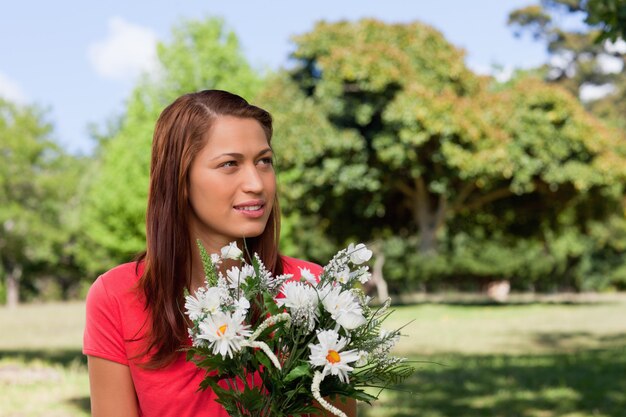 Mulher jovem, olhar, a, lado, enquanto, segurando, um, grupo flores