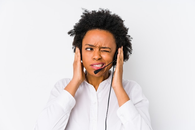 Mulher jovem operador de telemarketing americano africano isolado cobrindo as orelhas com as mãos.