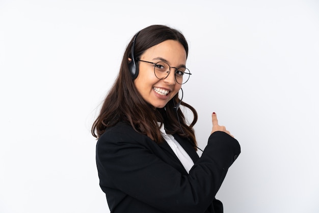 Foto mulher jovem operador de telemarketing na parede branca, apontando para trás