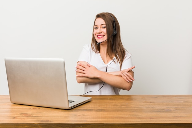 Mulher jovem operador de telemarketing que se sente confiante, cruzando os braços com determinação.