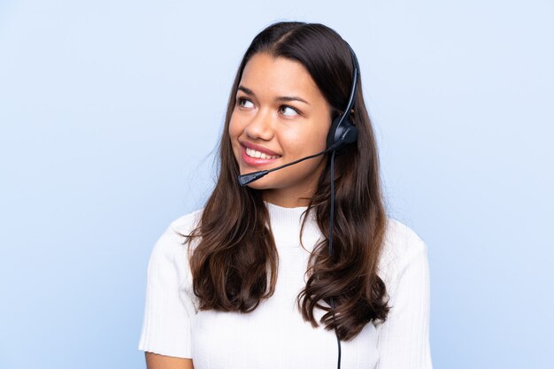 Mulher jovem operador de telemarketing sobre parede isolada