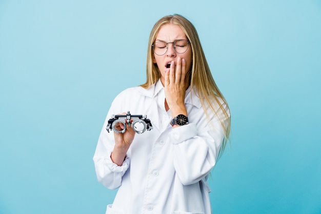 Mulher jovem optometrista russa bocejando azul mostrando um gesto cansado cobrindo a boca com a mão