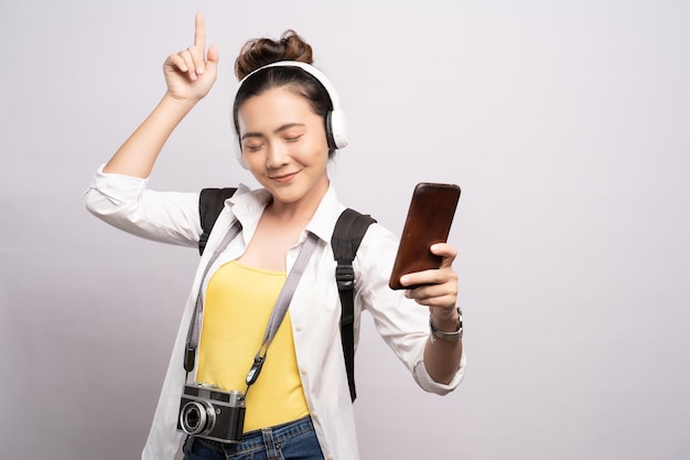 Mulher jovem ouvindo música através de fones de ouvido enquanto dança contra um fundo branco