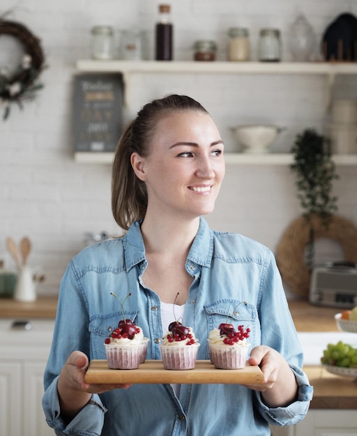 Mulher jovem padeiro segurando cupcakes