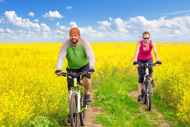 Mulher jovem pedalando em um campo de flores amarelas