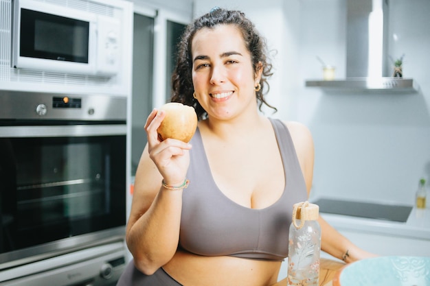 Mulher jovem plus size no sportswear segurando a maçã de comida saudável depois de malhar a sessão. Copie o espaço. Perder peso ganhando saúde em casa Comida, comendo bem, conceito de comida saudável Comida ecológica natural