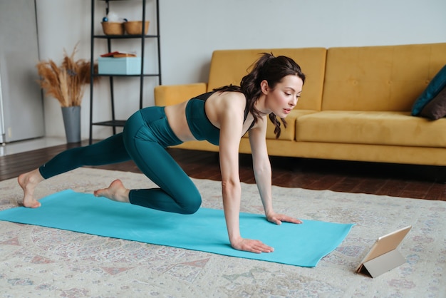 Mulher jovem praticando exercícios em casa