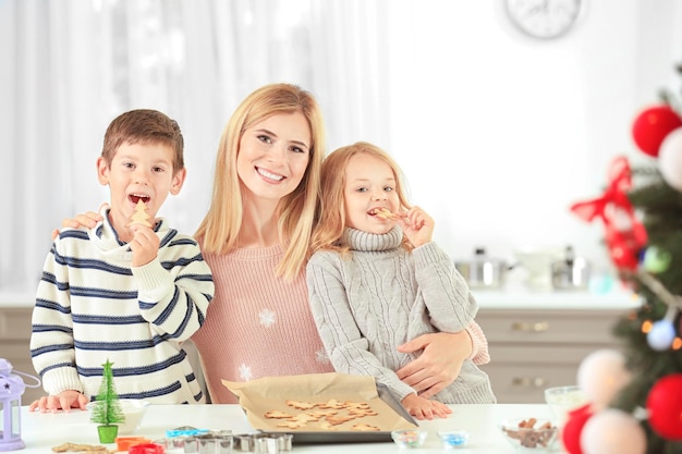 Mulher jovem preparando biscoitos de Natal com crianças pequenas na cozinha