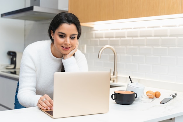 Foto mulher jovem procurando uma receita no computador