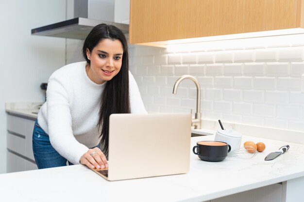 Foto mulher jovem procurando uma receita no computador