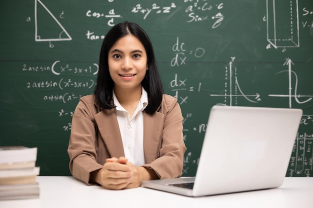 Mulher jovem professora asiática sentada usando videoconferência de laptop com estudante Professora treinando matemática em sala de aula a partir de transmissão ao vivo com curso on-line de computador