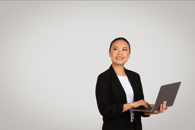 Foto mulher jovem profissional confiante em um blazer preto e camisa branca segurando um laptop