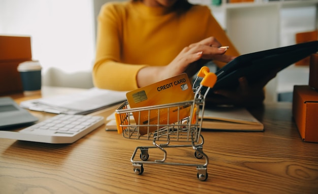 Foto mulher jovem proprietária de uma pequena empresa que faz compras on-line em casa e toma nota das encomendas dos clientes com telefones móveis