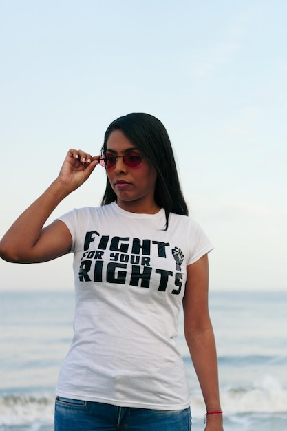 Mulher jovem protestando na praia com o punho erguido