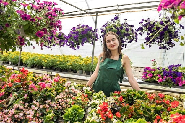 Mulher jovem que trabalha em uma estufa, cuidando de flores.