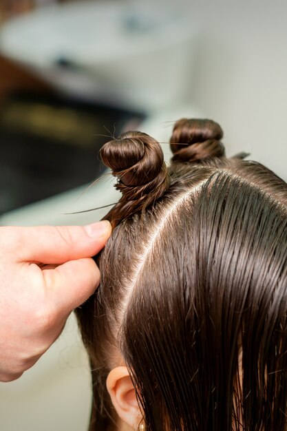 Mulher jovem recebe processo de penteado por cabeleireiro em salão de beleza