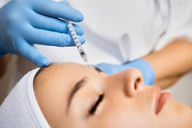 Mulher jovem recebendo uma injeção facial rejuvenescente na clínica aplicação profissional de botox