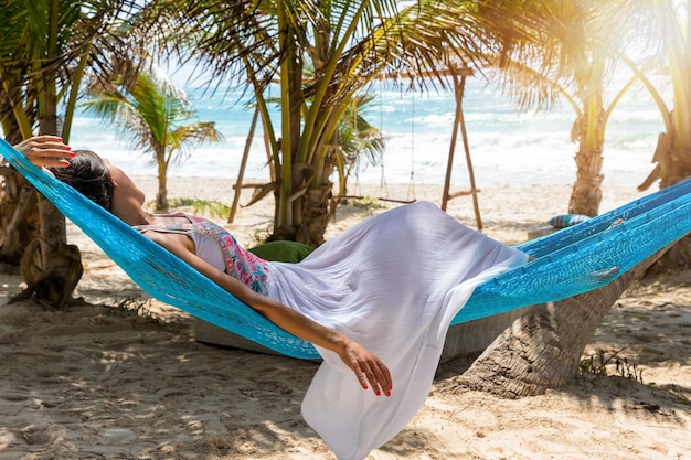 Mulher jovem relaxando em uma hamaca na praia