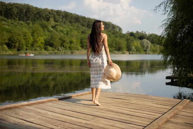 Mulher jovem relaxante em um píer de madeira no lago calmo