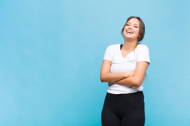 Mulher jovem rindo feliz com os braços cruzados