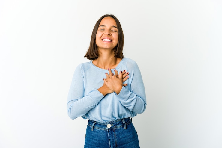 Foto mulher jovem rindo, mantendo as mãos no coração, conceito de felicidade