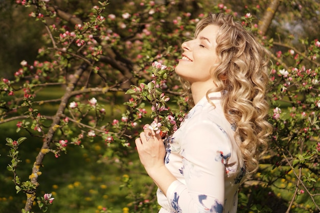 Mulher jovem romântica no jardim primavera entre flor de maçã. mulher linda feliz primavera