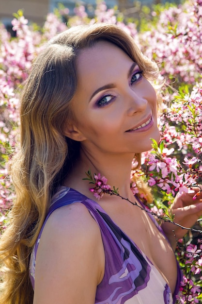 Foto mulher jovem rosas pequenas flores de amígdala de amêndoa em um dia ensolarado