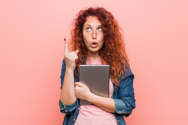 Mulher jovem ruiva caucasiano segurando um tablet tendo uma ótima idéia, conceito de criatividade.