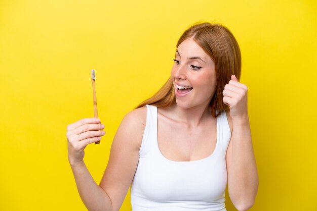 Mulher jovem ruiva escovando os dentes comemorando uma vitória