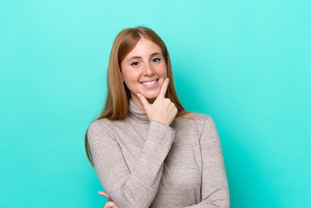 Mulher jovem ruiva isolada em fundo azul feliz e sorridente