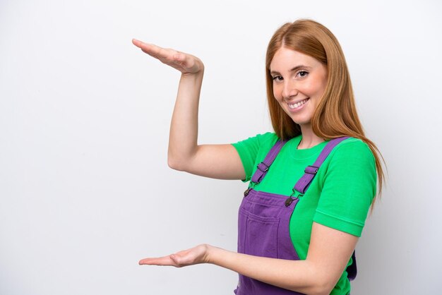 Mulher jovem ruiva isolada em fundo branco segurando copyspace para inserir um anúncio