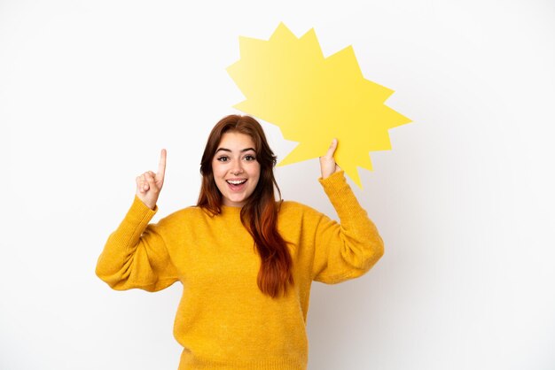 Mulher jovem ruiva isolada no fundo branco segurando um balão de fala vazio com expressão de surpresa