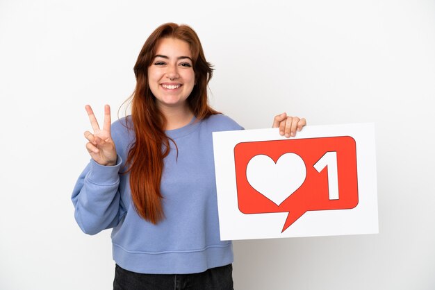 Foto mulher jovem ruiva isolada no fundo branco segurando um cartaz com o ícone 