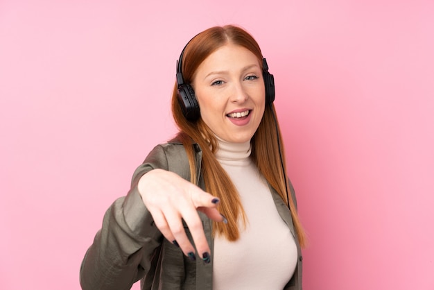 Mulher jovem ruiva isolada parede rosa ouvindo música