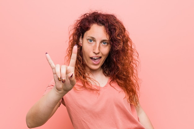 Mulher jovem ruiva natural e autêntica, mostrando um gesto de chifres