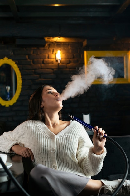 Foto mulher jovem saindo de um narguilé em um bar