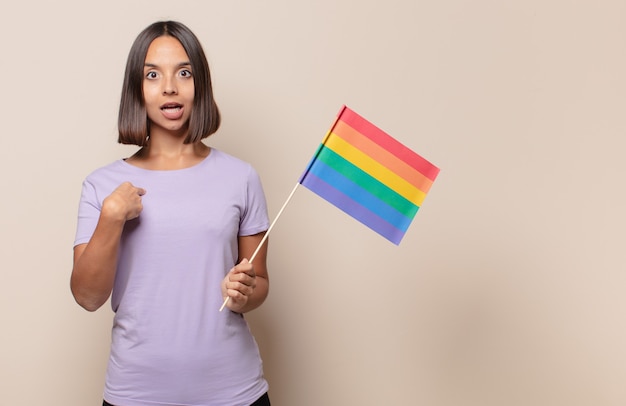 Mulher jovem se sentindo feliz, surpresa e orgulhosa, apontando para si mesma com um olhar animado e surpreso