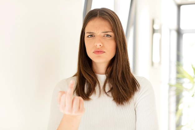 Mulher jovem se sentindo irritada, irritada, rebelde e agressiva girando o dedo do meio para lutar