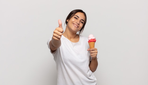 Mulher jovem se sentindo orgulhosa, despreocupada, confiante e feliz, sorrindo positivamente com o polegar para cima