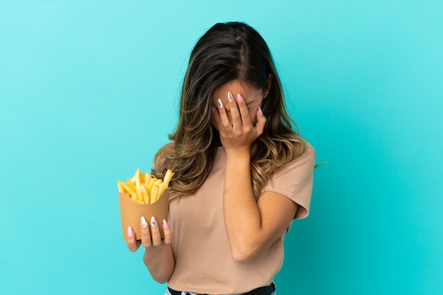 Foto mulher jovem segurando batatas fritas sobre um fundo isolado com uma expressão cansada e doente